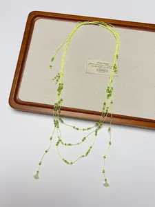 Detail of layered green beaded necklace with floral pendant and bohemian style