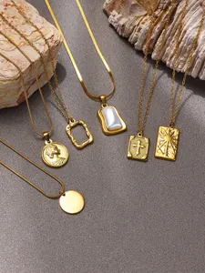 Detailed close-up of six gold stainless steel necklaces with assorted pendants on stone