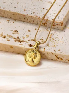 Macro view of gold-plated coin necklace featuring Elizabeth II portrait on stone background