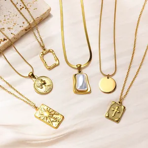 Collection of golden stainless steel necklaces with various pendants on stone background