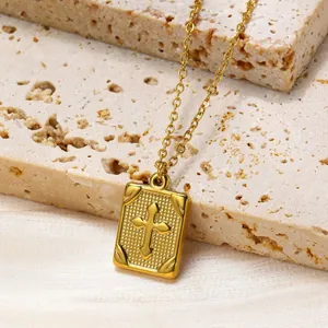 Gold stainless steel cross necklace with textured rectangular pendant on silk background