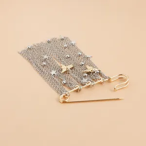 Dettaglio macro della spilla vintage con catene in argento e uccellini in oro lucido