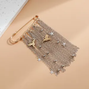 Dettaglio della spilla dorata con nappe a catena argentata e ciondoli a colibrì