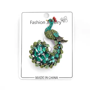 Detail of peacock brooch featuring green and blue crystals on a golden metal base