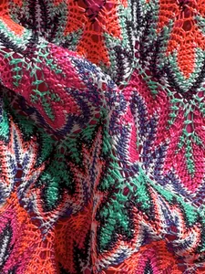 Close-up of vibrant crochet knit fabric with colorful leaf patterns and mesh texture
