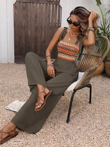 Detail of bohemian olive green jumpsuit featuring orange geometric embroidery accents