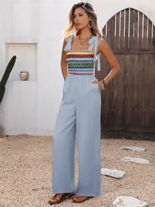 Detail of light blue wide-leg jumpsuit with colorful ethnic embroidery and lace-up straps