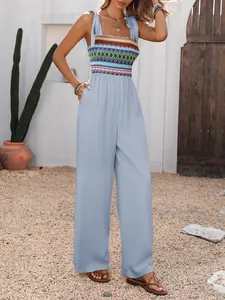Detail of bohemian jumpsuit showing colorful geometric embroidery and tie-up straps