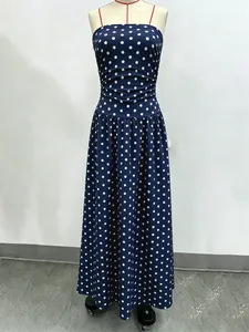 Detail of navy polka dot dress featuring slim red straps and pleated waist on mannequin