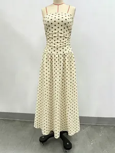 Detail of elegant beige off-shoulder polka dot maxi dress with a pleated waistline