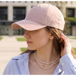 Detail of light pink quick-dry golf hat with geometric side logo and curved visor