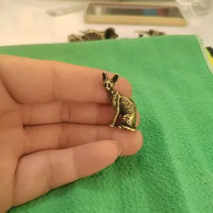 Macro detail of a miniature bronze Sphinx cat figurine held by hand for scale