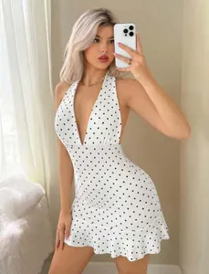 Detail of white polka dot halter dress with deep V-neck and ruffled hemline