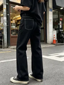 Dettaglio di jeans neri larghi con cuciture bianche a contrasto e tasche posteriori