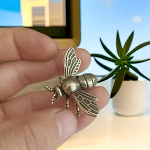 Detailed close-up of a vintage bronze bee figurine with fine engraved wing textures
