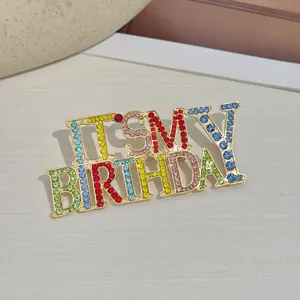 Détail macro de la broche dorée IT'S MY BIRTHDAY sertie de strass multicolores