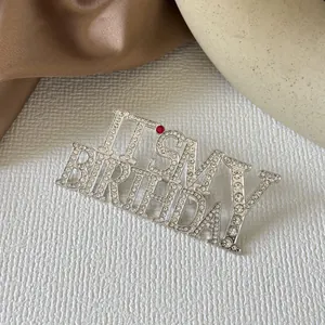 Vue détaillée de la broche strass IT'S MY BIRTHDAY avec finition argentée et cristal rouge