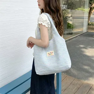 Detail of light blue knit tote bag with rainbow specks and woven texture finish
