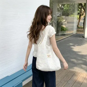 Outdoor lifestyle shot of a cream knitted tote bag with colorful specks and fabric patch