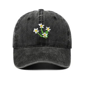 Close-up of delicate daisy flower embroidery on washed black cotton baseball cap