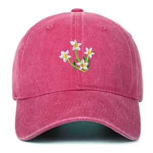 Close-up of small white daisy floral embroidery on magenta cotton baseball cap