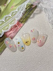 Detail of floral press-on nails with gold stars, pink gradients, and lace decor