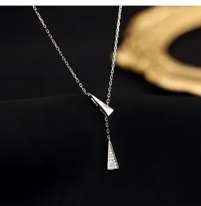 Macro detail of a silver Y-shaped necklace with geometric triangles and pave crystals