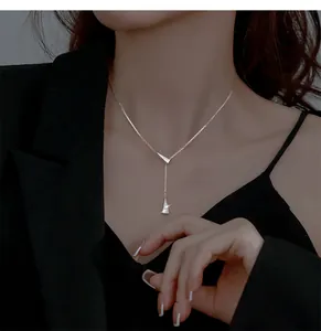 Close-up of silver geometric Y-shaped tassel necklace with sparkling CZ stones on black dress