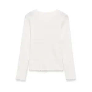 Macro view of white ribbed knit long sleeve top with delicate lettuce edge detailing