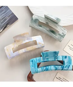 Three acrylic hair claws with marble textures in mint green, purple and blue