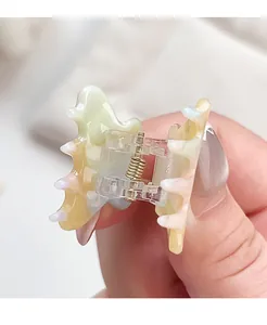 Detail of small acetate hair claw with pastel gradient marble texture and gold spring