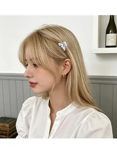 Detailed view of small spotted acetate hair claw and silver hoop earrings on a model