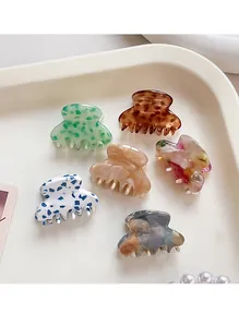 Set of six mini acetate hair claws with various floral and marble patterns on a tray