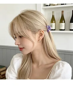 Close-up of a floral acetate hair claw and silver hoop earring on a model