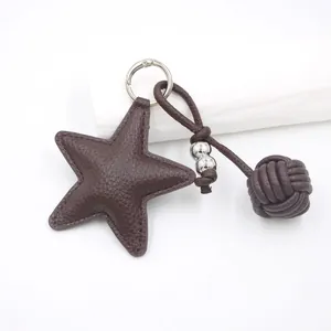 Detail of dark brown star-shaped leather keychain with woven ball and silver hardware