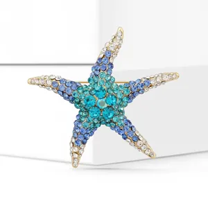 Detail of a starfish brooch with blue and white crystals in a gold-plated setting