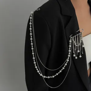 Detail of multi-layer fringe brooch with pearls and silver chains on black suit