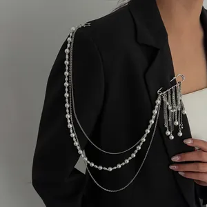 Detail of layered silver tassel chain brooch with white pearls on a black suit