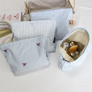 Close-up of striped makeup bags with bow embroidery and zipper in varied sizes