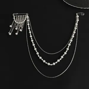 Detail of hip-hop style layered chain brooch with silver safety pins and pearls