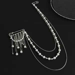 Detail of silver layered chain brooch with star charms and white pearls on black texture