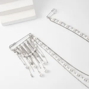 Detail of silver safety pin brooch with cascading pearl fringe and metal chains