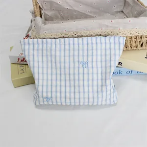 Detail of light blue plaid cosmetic bag with bow embroidery and zipper closure
