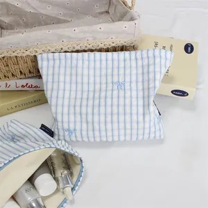 Blue and white striped cosmetic bag with detailed bow embroidery and soft fabric texture