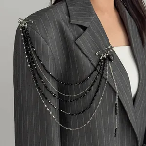 Detail of silver star tassel chain brooch with black beads on a gray striped blazer