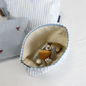 Detail of blue striped makeup bag with red bow embroidery and soft inner lining