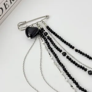 Macro view of silver tassel chain brooch with black heart pendant and faceted beads