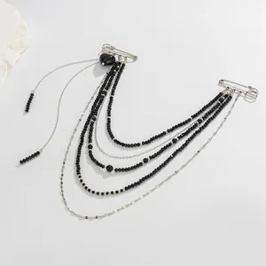 Macro view of gothic punk double pin brooch with black beads and layered silver chains