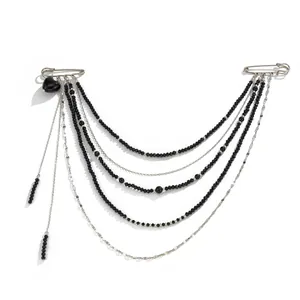 Detail of layered silver chains and black bead tassels on a punk style brooch pin