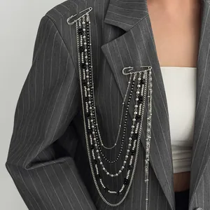 Detail of multi-layered silver and black bead chain brooch with star pins on suit